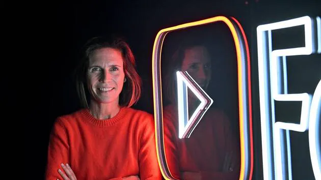 Justine Ryst, directeur général de YouTube, posant à côté du logo de la plateforme.